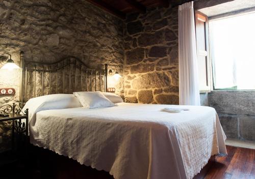 a bedroom with a bed with a stone wall at Casa de Costoia in Santiago de Compostela