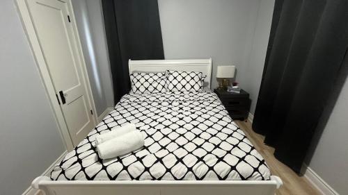 a bedroom with a white bed with a black and white comforter at Renovated Home - Walk to Falls & Tourist District in Niagara Falls