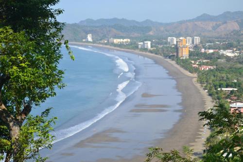 Una vista de una playa con una ciudad al fondo. en 3 Bedroom Condo with Ocean View - Tres Regalos 201N, en Jacó