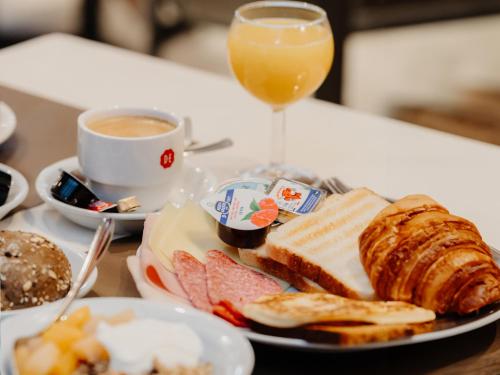 a plate of food with bread and a glass of orange juice at Domein Westhoek in Oostduinkerke