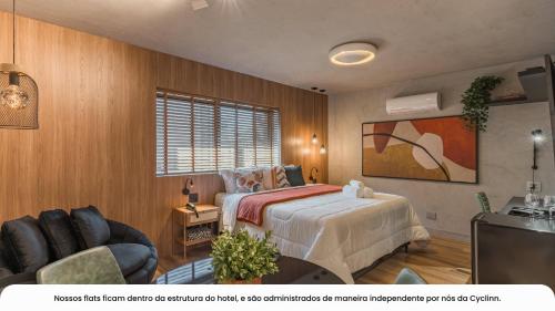 a bedroom with a bed and a couch and a television at Cyclinn Bela Cintra Jardins in Sao Paulo