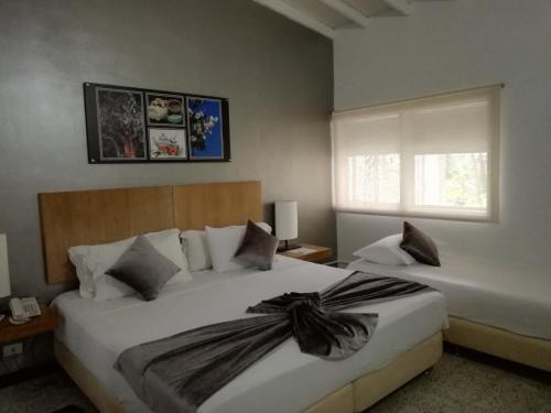 a bedroom with two beds and a window at Hotel Aromax del Campestre in Medellín