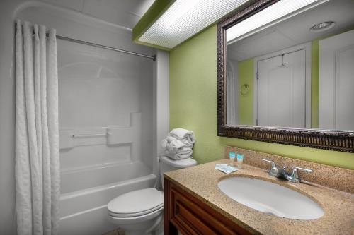 a bathroom with a sink and a toilet and a mirror at Monterey Bay Suites in Myrtle Beach