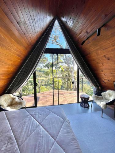 a bedroom with a bed and a large window at Pousada Cabanas Araxá in Urubici