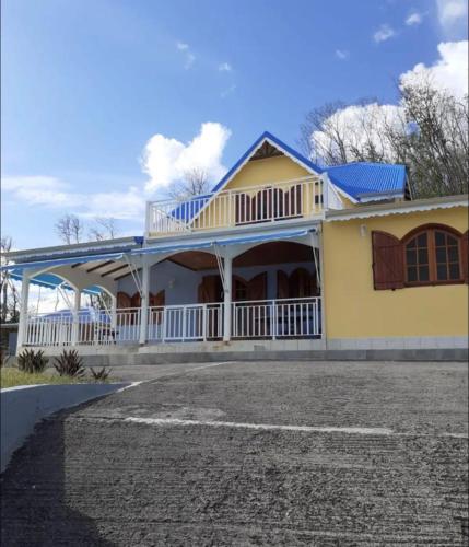 une maison jaune et blanche avec une terrasse couverte dans l'établissement Superbe villa, à Bouillante