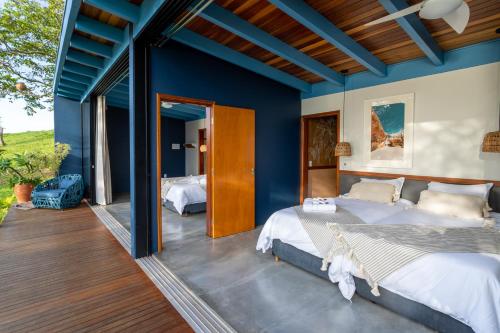 two beds in a bedroom with blue walls at @morro.redondo - A casa Azul e seu Pôr do Sol in CÃ¡ssia