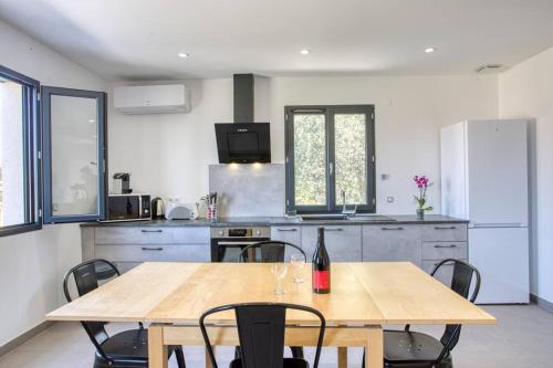 a kitchen with a table with a bottle of wine on it at Appartement neuf Bédoin - Les Cinglés du Mont Ventoux in Mormoiron