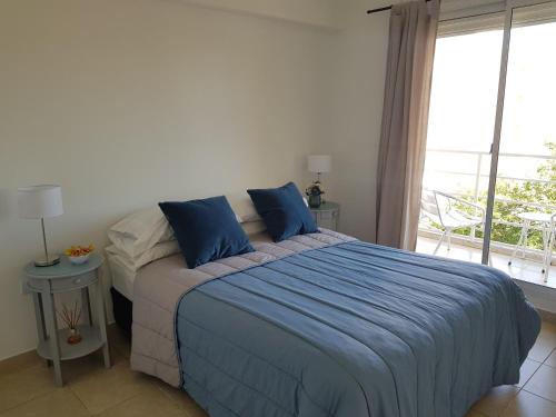 1 dormitorio con cama con sábanas azules y ventana en Departamento Talero con cochera en Neuquén