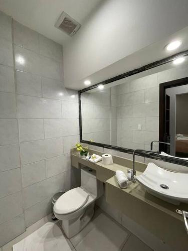 y baño con aseo, lavabo y espejo. en Moderno y acogedor condominio, en San Pedro Sula