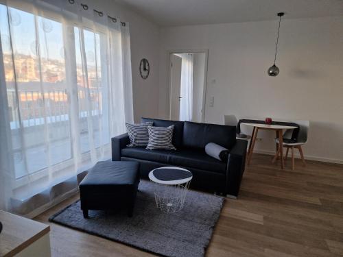 a living room with a black couch and a table at Auszeit Penthouse-Feeling in Esslingen