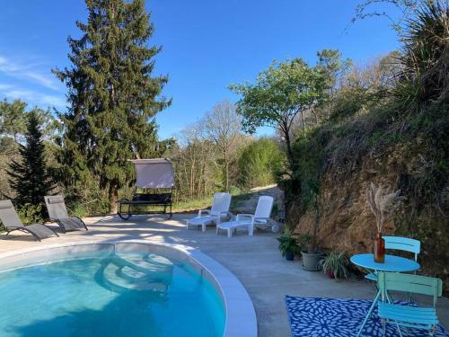 une piscine avec des chaises et une table ainsi qu'une terrasse dans l'établissement Les hyacinthes, à Sarlat-la-Canéda