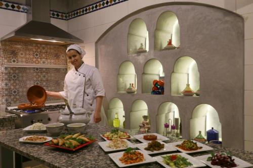 a chef standing in a kitchen preparing food at Ryad El Borj in Marrakech