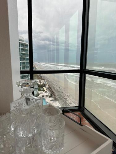 a view of the ocean from a window with wine glasses at beautiful oceanfront two bedroom condo in Daytona Beach