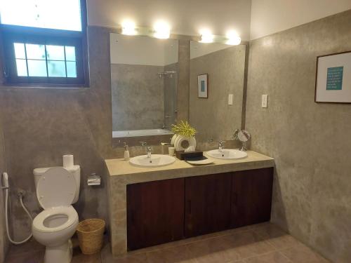 a bathroom with two sinks and a toilet and a mirror at Ranna Beach House in Ranna
