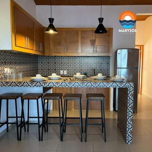 a kitchen with a counter with stools and a refrigerator at MarySol Las Palmas in Rincon de Guayabitos