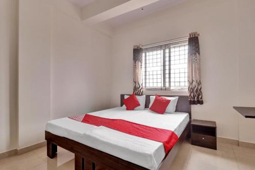 a bedroom with a bed with red pillows and a window at OYO Flagship 81553 Green Residency in Bangalore