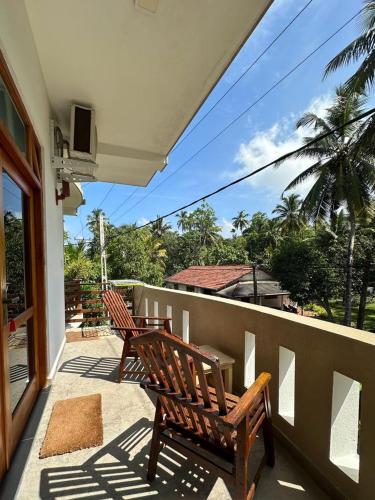 two wooden benches sitting on a balcony with a view at Siyon Yula - Guest House in Hikkaduwa