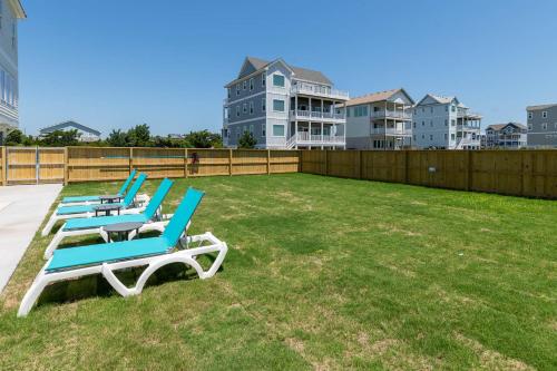 a row of lounge chairs on a lawn with buildings at Zensation 14 Bedroom Home by KEES Vacations in Salvo