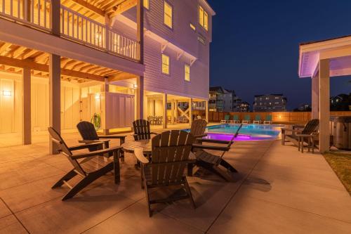 a patio with chairs and a table and a swimming pool at Zensation 14 Bedroom Home by KEES Vacations in Salvo