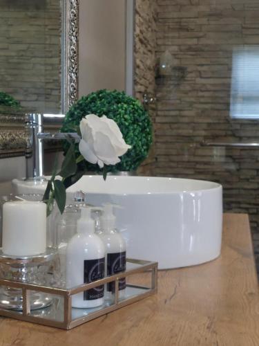 a bathroom counter with a white rose and bottles of soap at Bella Rosa in Potchefstroom