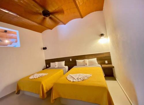 two beds in a room with yellow sheets at MarySol Las Palmas in Rincon de Guayabitos