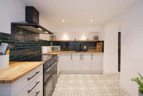 uma cozinha com armários brancos e piso em azulejo em The Haze House - 4 Bed Townhouse em Bath