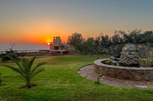 a sunset over a yard with a fountain in the grass at Villa Kore Elafonissi in Ãyios FÃ³tios