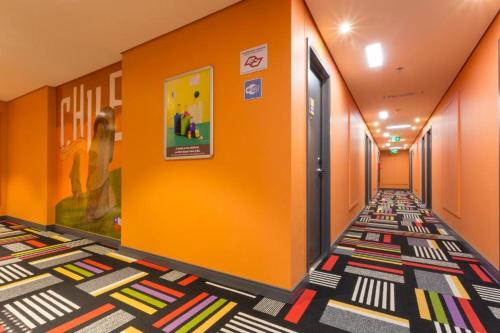 un pasillo con paredes de color naranja y una alfombra colorida en ibis Styles Sao Paulo Barra Funda, en São Paulo