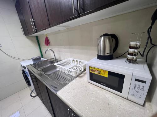 a kitchen counter with a microwave and a sink at Single bed hosted by dinar apartments in Abu Dhabi