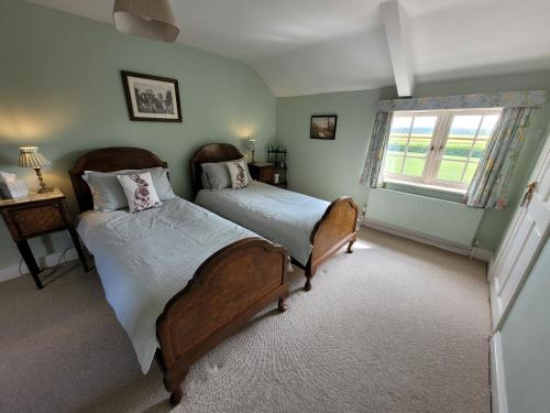 a bedroom with two beds and a window at Burton Grange Farmhouse Bed and Breakfast in Boroughbridge