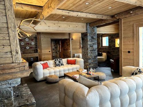 a living room with white furniture and a stone fireplace at chalet ormelune au pied des pistes in Sainte-Foy-Tarentaise