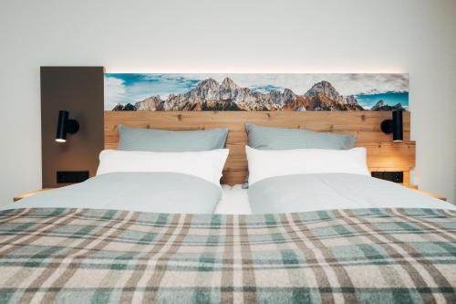 two beds in a hotel room with mountains on the wall at Living Mountain Tannheim in Tannheim