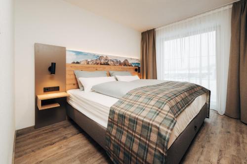 a bedroom with a large bed with a painting on the wall at Living Mountain Tannheim in Tannheim