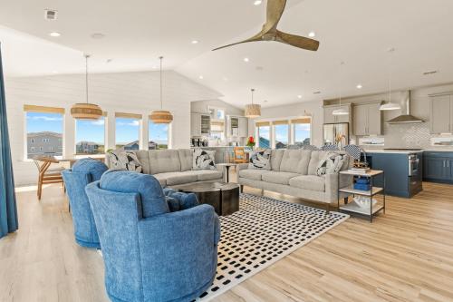 a living room with blue chairs and a kitchen at Zensation 14 Bedroom Home by KEES Vacations in Salvo