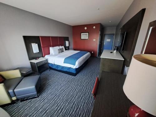 um quarto de hotel com uma cama e uma cadeira em Del-Mar Airport Inn & Suites em Shreveport