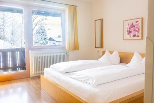 Cama blanca en habitación con ventana en Hotel Garni Landhaus Sonnenstern en Schönau am Königssee