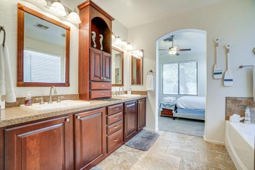 a bathroom with a sink and a tub and a bathroom with a bed at Goodyear Home with Pool, 6 Mi to Spring Training! in Goodyear