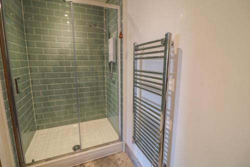 a shower in a bathroom with green tiles at Valley View in St Austell