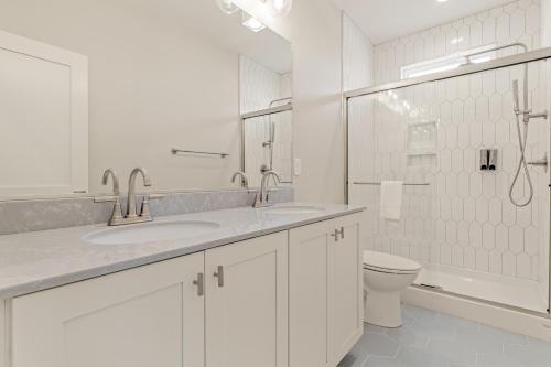 a white bathroom with two sinks and a toilet at Zensation 14 Bedroom Home by KEES Vacations in Salvo