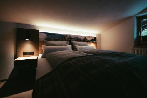 a bedroom with a large bed with a painting on the wall at Living Mountain Tannheim in Tannheim
