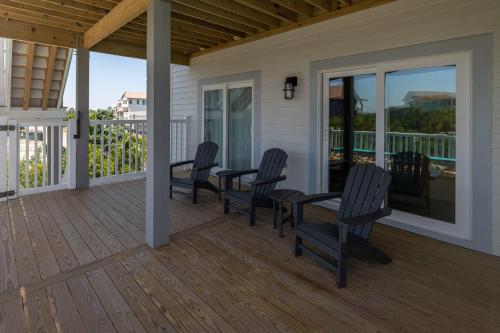 a porch with chairs and a table on a deck at Zensation 14 Bedroom Home by KEES Vacations in Salvo