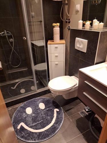 a bathroom with a toilet and a smiley face rug at Vila Irina Kopaonik in Kopaonik