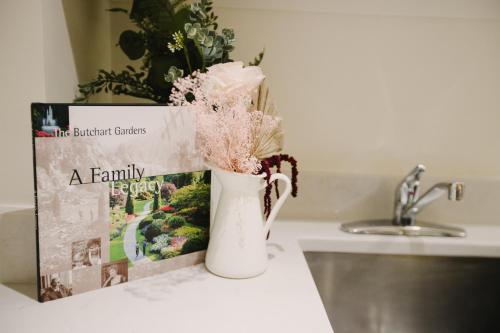 um vaso com flores num balcão ao lado de uma revista em The Garden Room at Waddington Flats em Victoria