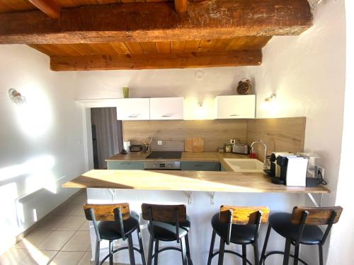 a kitchen with a counter with four bar stools at Esprit Bohème in Fayence