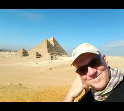 a man wearing sunglasses and a hat in front of pyramids at Nana Pyramids Guest House in Cairo
