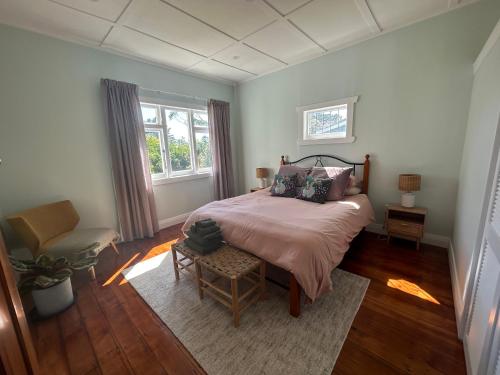 a bedroom with a bed and a chair and a window at Green Turtle Cottage in Pukenui