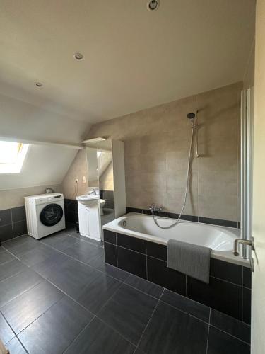a bathroom with a tub and a washing machine at The 40 work or holiday new Appt in Comines