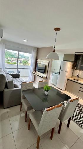 uma cozinha e sala de estar com mesa e cadeiras em Condomínio Vista Atlântico - Apartamento Novo - Próximo à Praia - Vista Mar - Área de Lazer em Itapema