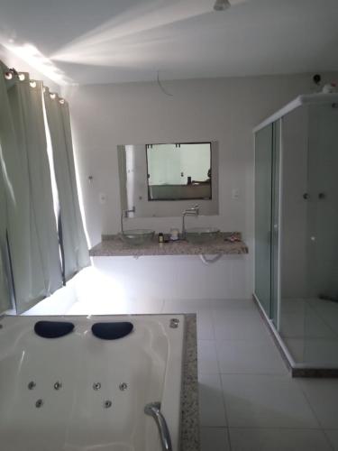La salle de bains blanche est pourvue d'un lavabo et d'un miroir. dans l'établissement R&L Pousada, à Cabo Frio
