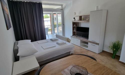 a white room with a bed and a television at Apartmani Sunce i More in Premantura